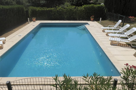 Une cl&ocirc;ture s&eacute;pare l'espace jardin de la piscine.