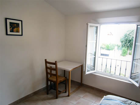 Une chaise et une table carr&eacute;e accompagnent le lit de cette grande chambre.